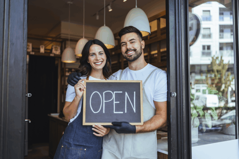 Colorado family-run business standing at shop entrance holding open sign, representing local SEO case study success with Acquire.